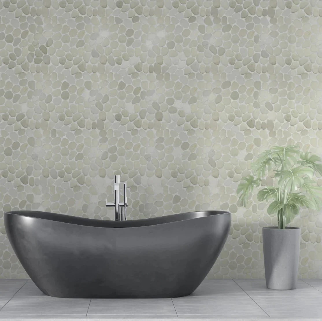 White pebble tile wall with grey bathtub and small plant in front of it